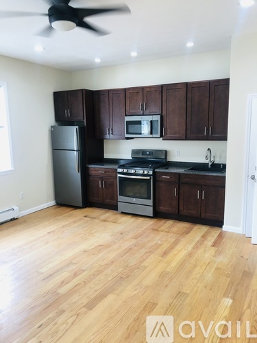 A kitchen with wooden floors and dark brown cabinets.