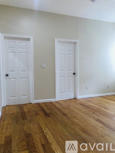 A room with two white doors and wooden flooring.