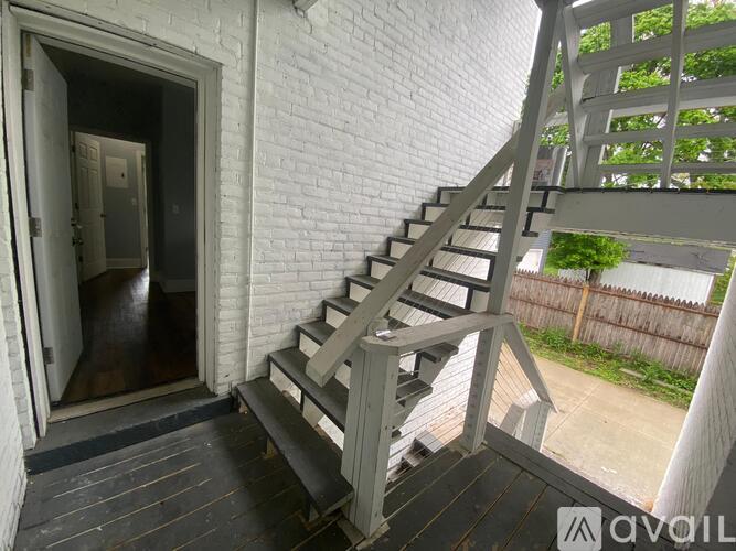 A white brick house with a staircase leading to a door.