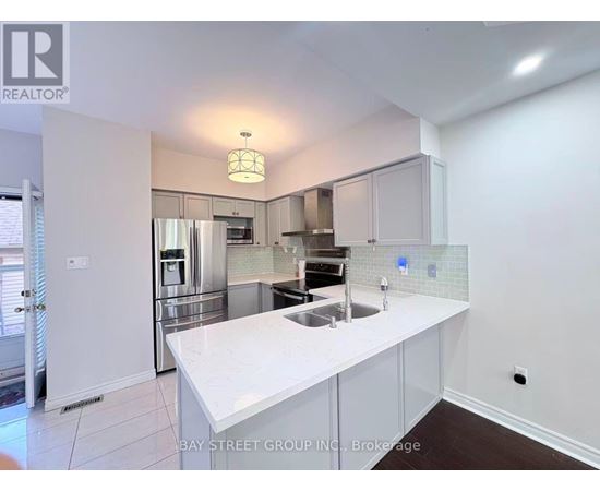 A white kitchen with a sink and a refrigerator.