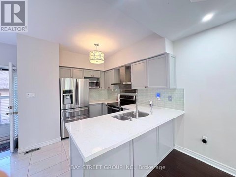 A white kitchen with a sink and a refrigerator.