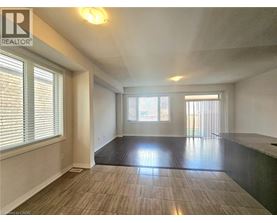 A spacious room with a large window and a wooden floor.