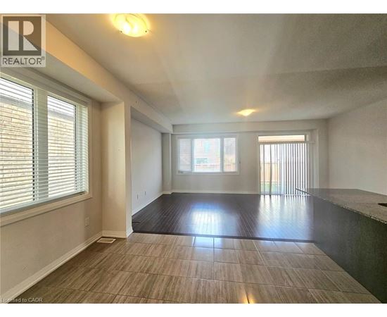 A spacious room with a large window and a wooden floor.