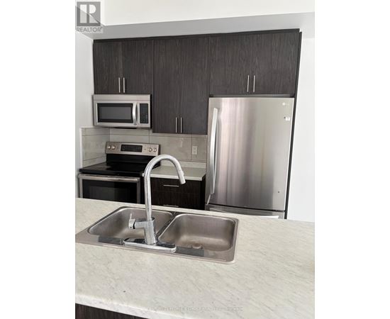 A modern kitchen with a stainless steel refrigerator and a double sink.