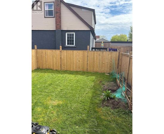 A backyard with a wooden fence and a small tree.