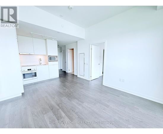 A spacious living room with a kitchen area in the background.