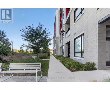 A white bench is on a concrete walkway in front of a building.