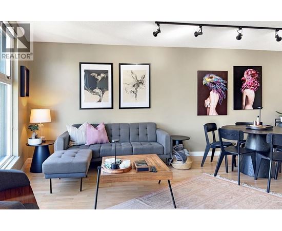 A living room with a grey sofa, a coffee table, and a dining table with chairs.