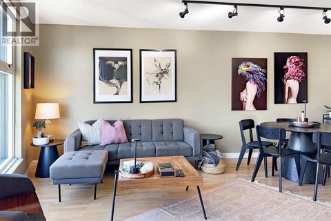 A living room with a grey sofa, a coffee table, and a dining table with chairs.