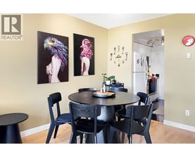 A dining room with a table and chairs and two paintings on the wall.