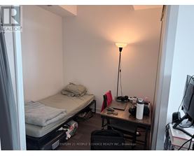 A small room with a bed, desk, and lamp.