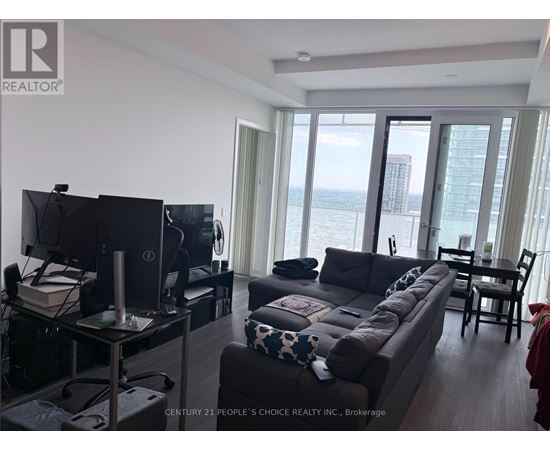 A living room with a flat screen TV and a large window overlooking the water.