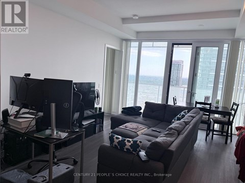 A living room with a flat screen TV and a large window overlooking the water.