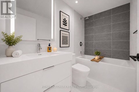 A white bathroom with a toilet, sink, and a plant.