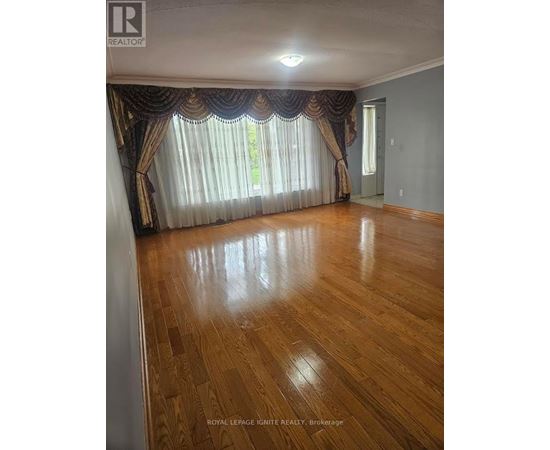 A room with wooden flooring and curtains on the window.