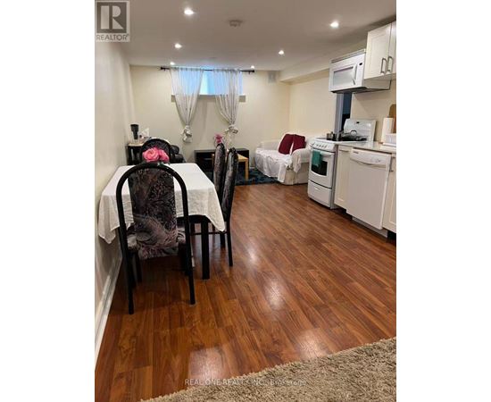 A kitchen with a table and chairs in the foreground and a bed in the background.