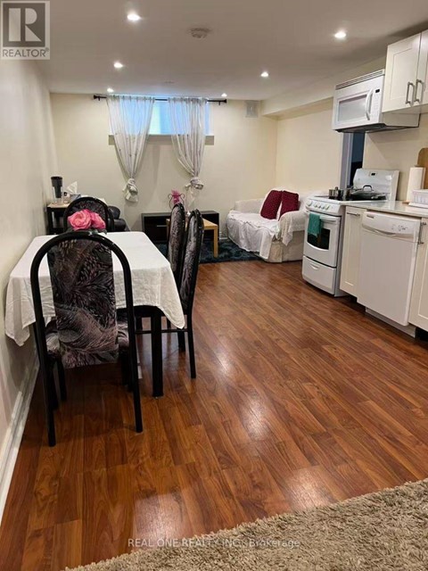 A kitchen with a table and chairs in the foreground and a bed in the background.