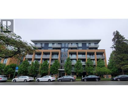 A large apartment building with cars parked in front.