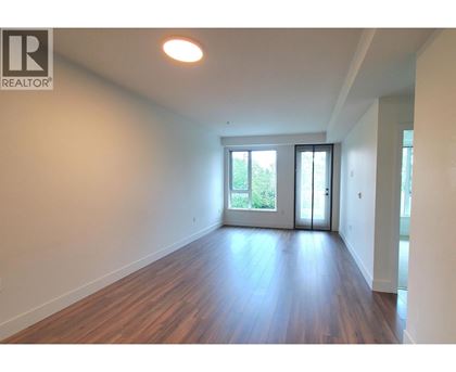 A room with wooden floors and white walls, with a sliding glass door leading outside.