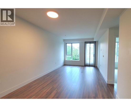 A room with wooden floors and white walls, with a sliding glass door leading outside.