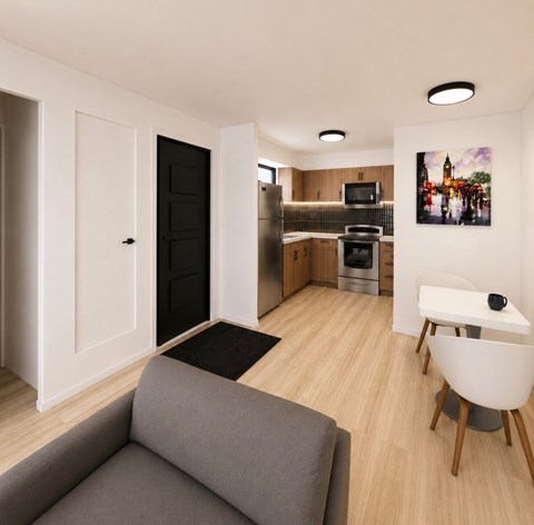 A modern living room with a grey couch and a kitchen area in the background.