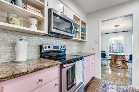 A kitchen with pink cabinets and a granite countertop.