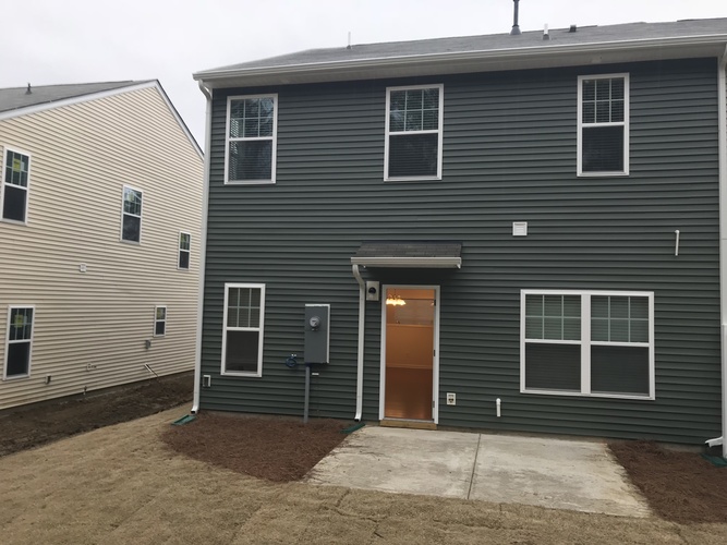 A grey house with a brown door and a brown garage door.