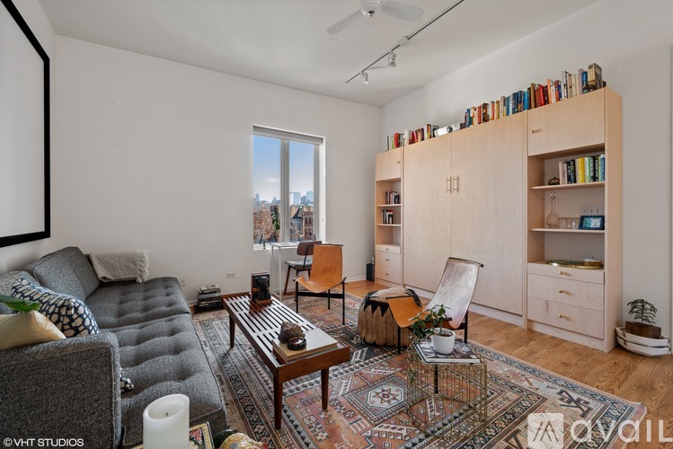 A living room with a grey sofa, a wooden coffee table, and a bookshelf filled with books.