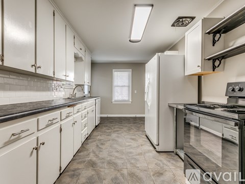 A kitchen with white cabinets and a black countertop.