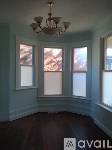 A room with a chandelier and three windows.