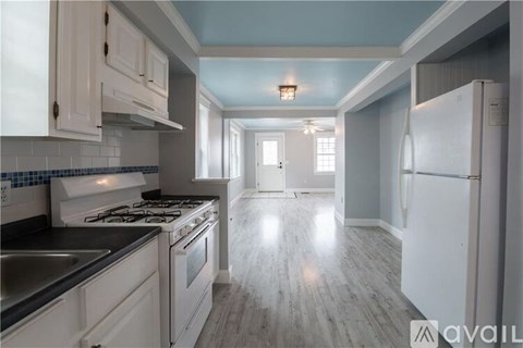 A kitchen with white cabinets and a stove top oven.