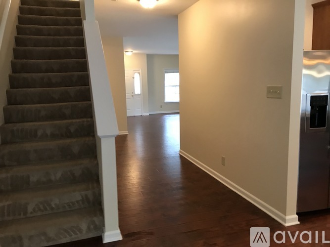 A hallway with a staircase on the left and a door on the right.
