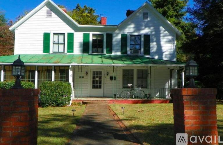A white house with green shutters and a green roof.