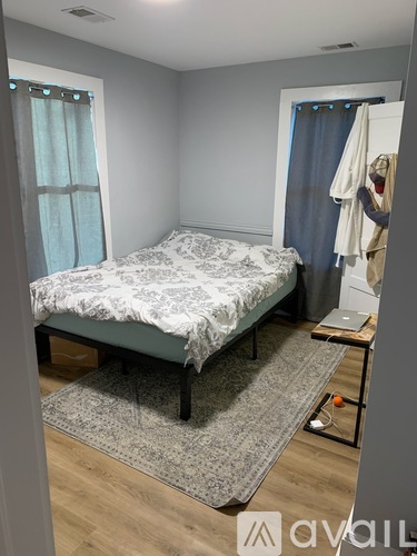 A bedroom with a bed, a laptop, and a rug.