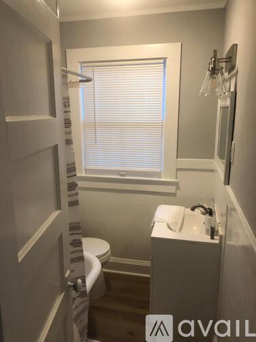 A bathroom with a toilet, sink, and a window with blinds.