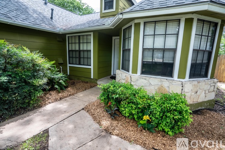 A house with a green and white exterior and a stone pillar in the front yard.