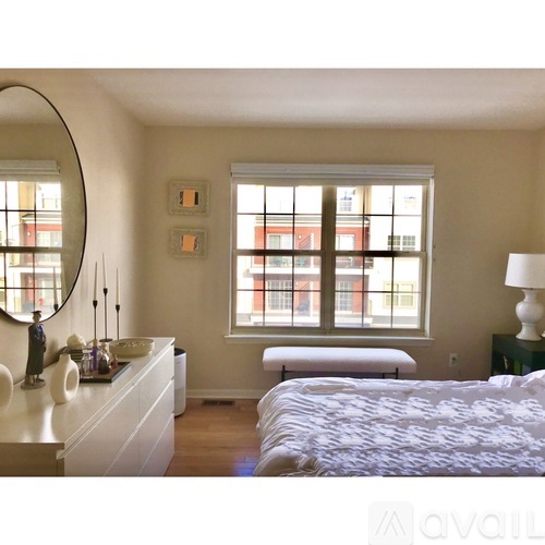A bedroom with a large bed, a vanity with a mirror, and a window with a view of a building outside.