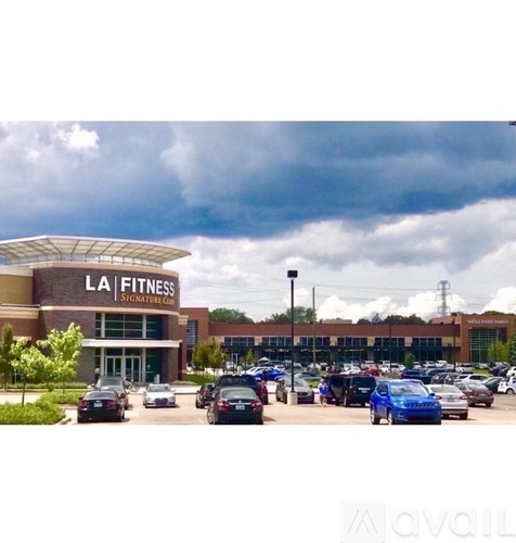 A fitness center with cars parked in front.