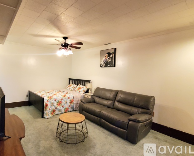 A bedroom with a bed, a couch, and a ceiling fan.