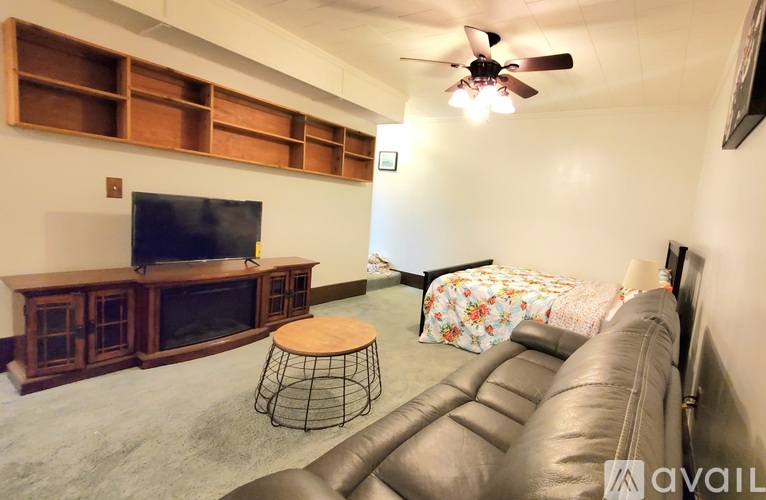 A living room with a brown leather couch and a wooden entertainment center.