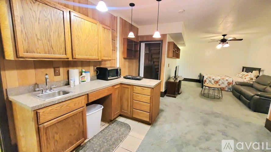 A kitchen with wooden cabinets and a countertop with a sink and a microwave.