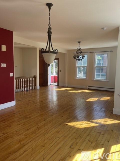 A large room with wooden floors and a chandelier hanging from the ceiling.