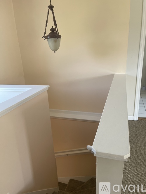 A white staircase with a light hanging from the ceiling.