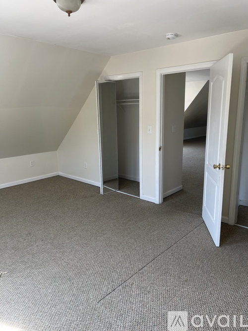 A room with a carpeted floor and two open doors.