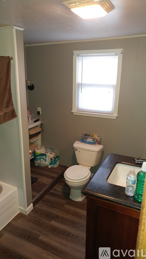 A bathroom with a toilet, sink, and a window.