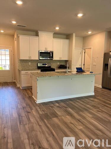 A kitchen with wooden floors and white cabinets.