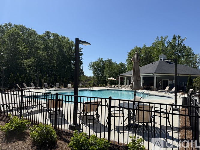A pool surrounded by a black fence with a house in the background.