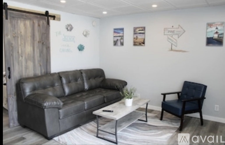 A living room with a black leather couch, a coffee table, and a chair.