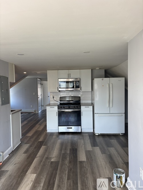 A modern kitchen with white appliances and wood flooring.