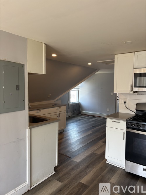 A kitchen with white cabinets and a wooden floor.